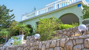 A building with a white balcony, stone wall, and a sign indicating a restaurant. - Vacation home Alma by Interhome (Karlobag)