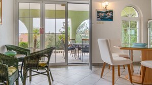 A room with a glass door leading to an outdoor area, wicker chairs, a wooden table, and a painting on the wall. - Vacation home Alma by Interhome (Karlobag)