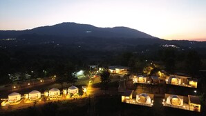 A series of dome-shaped yurts with a central building, surrounded by a mountainous landscape. - yugencamping (Khao Kho)