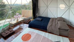 A tented accommodation with a bed, a table with flowers, and a view of the outdoors. - yugencamping (Khao Kho)