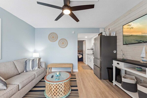 A living room with a sofa, round coffee table, and a ceiling fan.