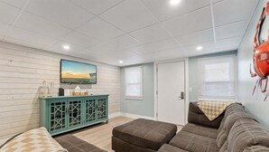 Un salon comprenant un canapé, un meuble, une télévision et une porte.