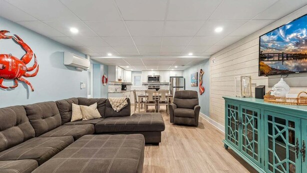 Un salon avec un canapé d’angle, un meuble de couleur turquoise et un grand téléviseur à écran plat.