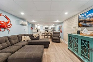 Un salon avec un canapé d’angle, un meuble de couleur turquoise et un grand téléviseur à écran plat.
