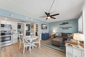 A compact living space with a kitchenette, dining area, and a seating area with a ceiling fan.