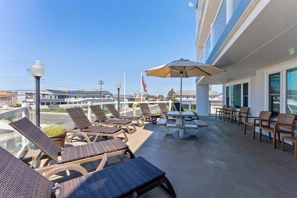 Ein Hotelbalkon mit Liegestühlen, einem Picknicktisch und einer amerikanischen Flagge.