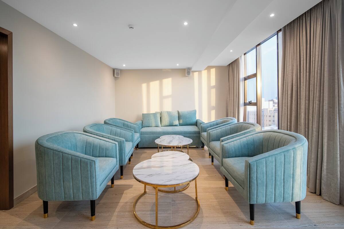 A modern living room with a sectional sofa, two round coffee tables, and large windows with curtains.