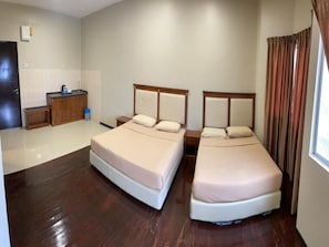 A hotel room with two single beds, a small kitchenette, a wooden cabinet, and a window with curtains. - Capital O 91107 Pd Tiara By Delima Suite (Port Dickson)
