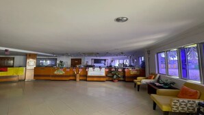 A spacious lobby with a reception desk, seating area, and large windows.