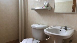 A bathroom with a toilet, sink, and a mirror.