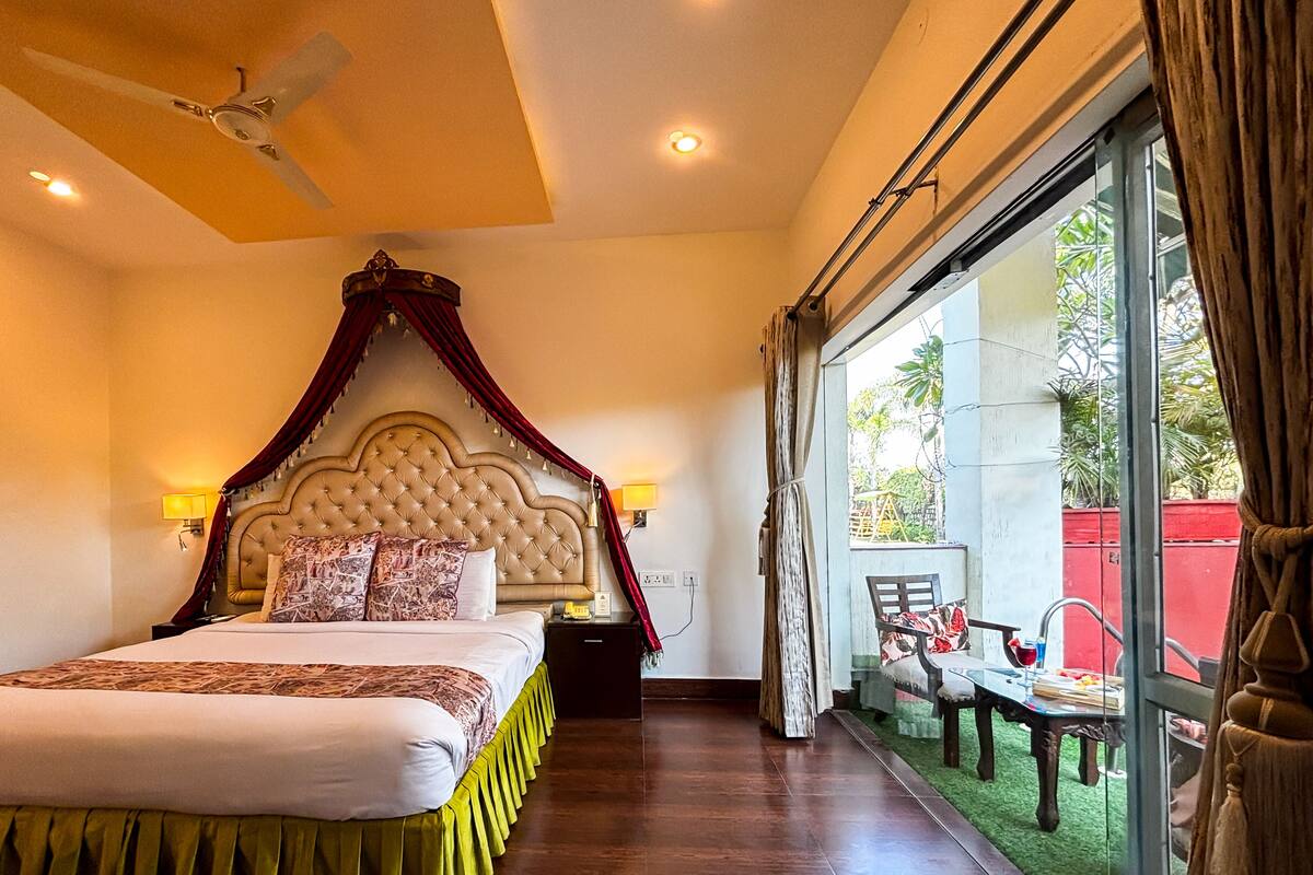 Ein Schlafzimmer mit Himmelbett, Deckenventilator und Blick auf den Balkon.