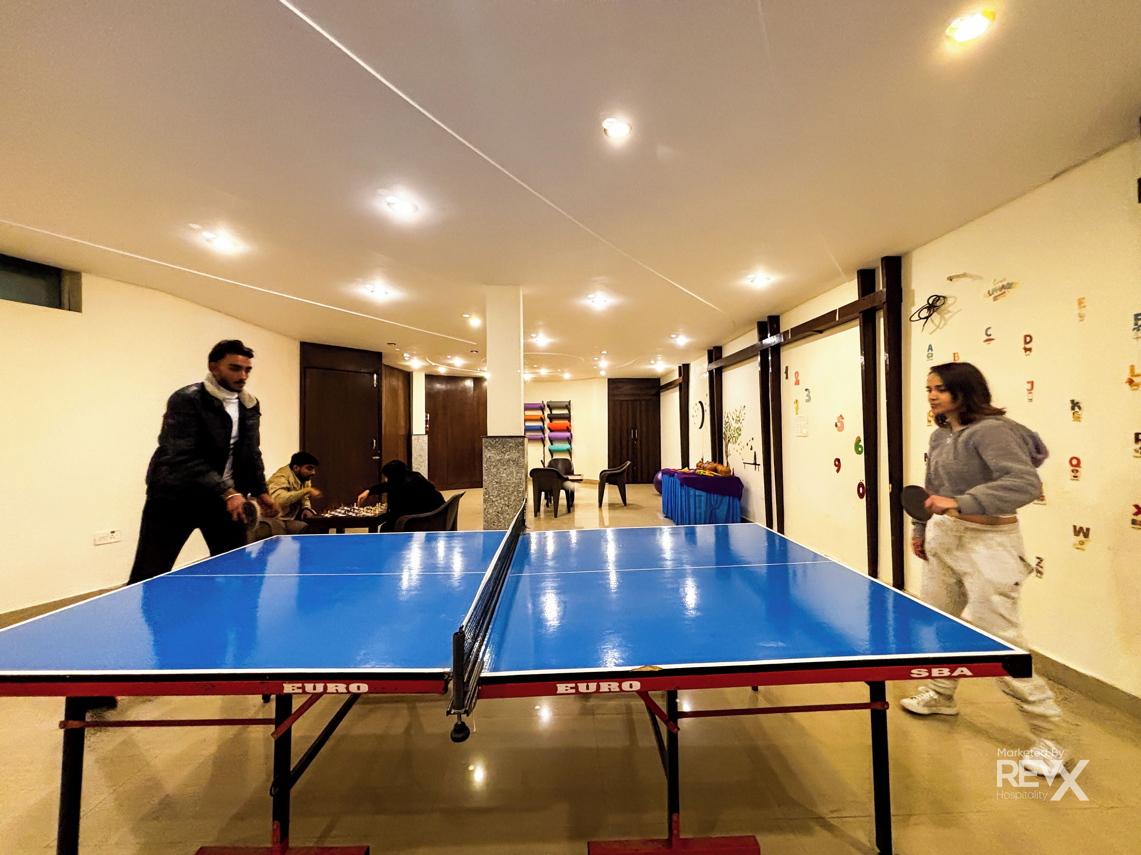 A room with a ping pong table, a seating area, and a wall with alphabet decorations.