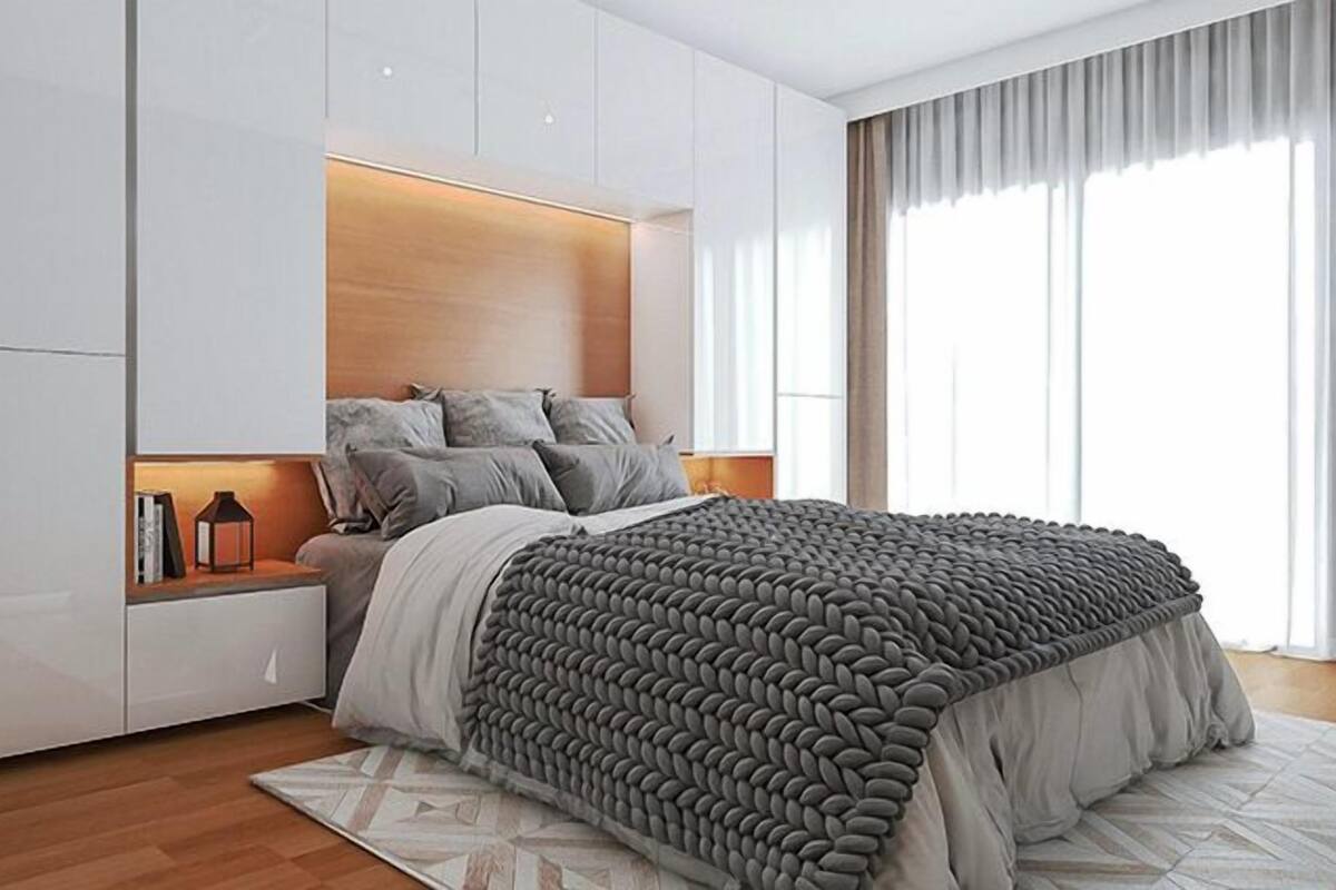 A modern bedroom with a large bed, built-in storage, and a view of the outdoors.