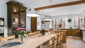 A dining area with a large table, wooden chairs, and a vase of flowers. There is a cabinet with glassware and a clock on the wall. - "Eva" - 9km to the fjord by Interhome (Brovst)