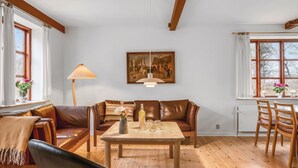 A living room with a brown leather sofa, a wooden coffee table, and a painting on the wall. - "Eva" - 9km to the fjord by Interhome (Brovst)
