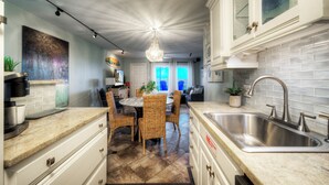 Una cocina moderna con una isla grande, armarios blancos y un lavamanos de acero inoxidable.
