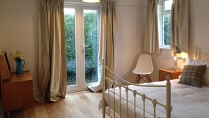 Um quarto com uma cama, uma escrivaninha, uma cadeira, uma mesa de cabeceira e uma janela com cortinas.