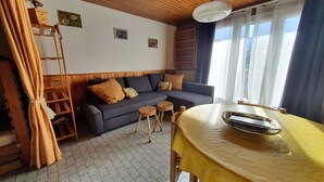 Een gezellige woonkamer met een bank, houten bijzettafeltje en een eettafel.