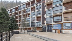 A multi-story hotel with balconies, a covered outdoor area, and a sign for a nearby shop. - Ski-Side Stay in Orcières (Orcières)