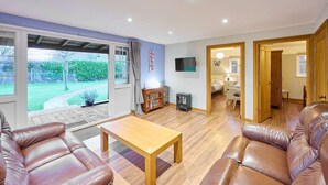 A spacious living room with leather sofas, a wooden coffee table, and a TV mounted on the wall. - Host Stay Dovecote View (Norwich)