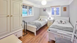 A bedroom with two beds, a wardrobe, and a window. - Host Stay Dovecote View (Norwich)