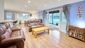A spacious living room with leather sofas, a wooden coffee table, and a bookshelf. - Host Stay Dovecote View (Norwich)