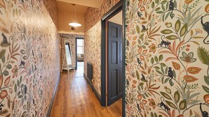 A hallway with patterned wallpaper and wooden flooring, leading to a room with a door. - Host Stay Apartment 1 St Stephens Court (Worcester)