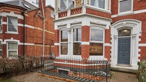 A red brick house with white trim, a black metal fence, and a grey door. - Host Stay Apartment 1 St Stephens Court (Worcester)