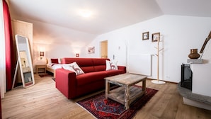 A cozy living room with a red sofa, a wooden coffee table, and a patterned rug. - Am Schloss Guest House (Brunico)