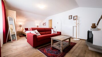 Una sala de estar acogedora con un sofá rojo, una mesa de centro de madera y una alfombra estampada.