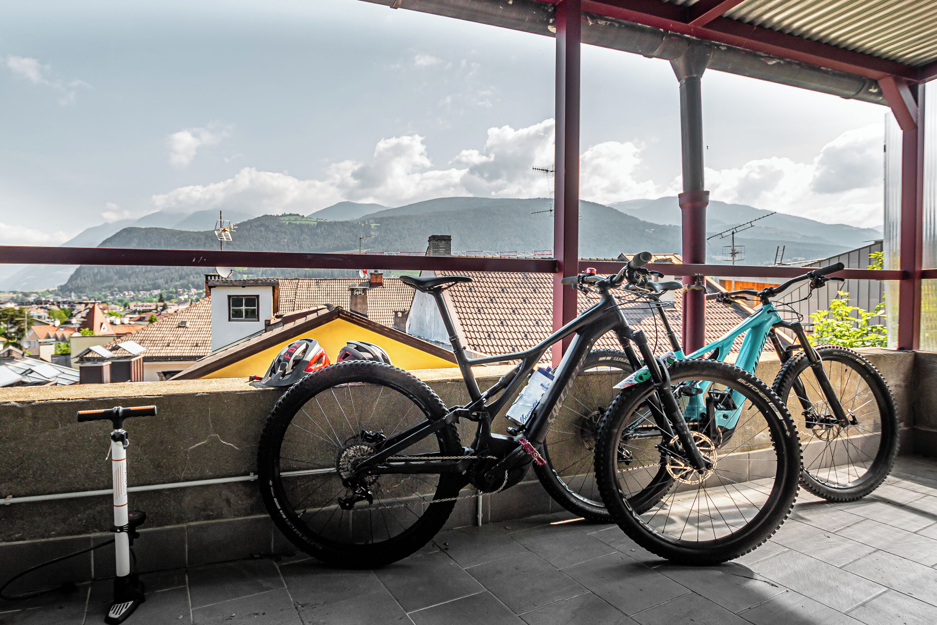 Ein Fahrrad steht auf einem Balkon mit Blick auf Berge und Gebäude.