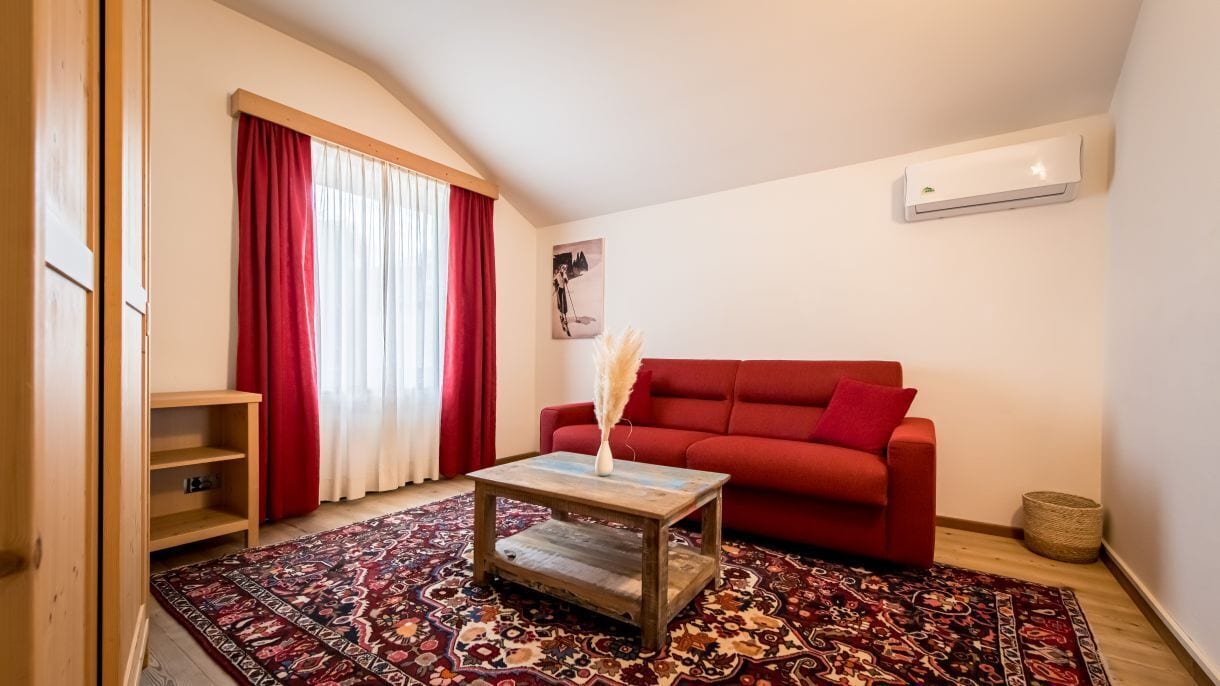 Un salon chaleureux avec un canapé rouge, une table basse en bois et un tapis à motifs.