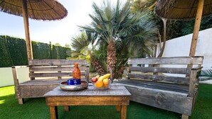 Un espacio al aire libre con mesa de madera, bancos y un frutero.