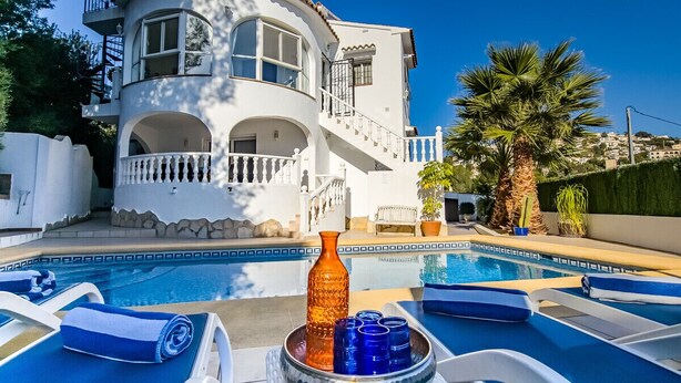 Un área de piscina con sillones de descanso y un jarrón decorativo.