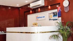 A reception desk with a white marble top, a clock, and a potted plant. - Hotel Konark Nest (Indore)
