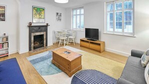 En stue med pejs, fjernsyn, sofa og spiseplads.