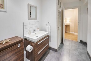 A modern bathroom with a white sink, wooden vanity, and a mirror. - Host Stay Garden Flat (Brighton)