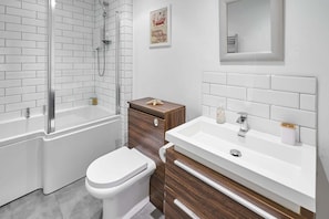 A modern bathroom with a glass-enclosed shower, a white toilet, and a wooden vanity with a sink.