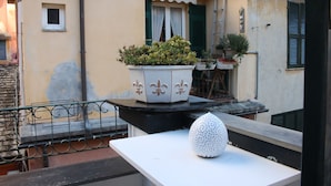 A balcony with a white table, a potted plant, and a decorative vase. - Portofino's Cozy Terrace Wi-fi A/C (Portofino)