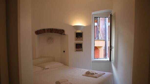 A bedroom with a bed, a window, and a wall-mounted shelf. - Portofino's Cozy Terrace Wi-fi A/C (Portofino)