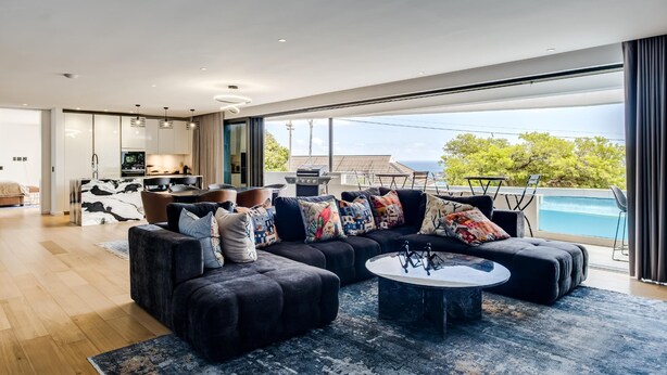A modern living room with a sectional sofa, a coffee table, and a view of a swimming pool.