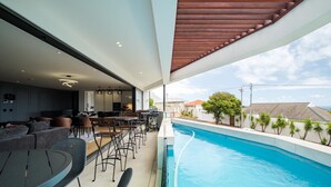 A modern outdoor pool area with a dining setup and a view of the surrounding neighborhood.