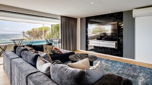 A modern living room with a large sofa, a coffee table, and a TV mounted on a black marble wall.