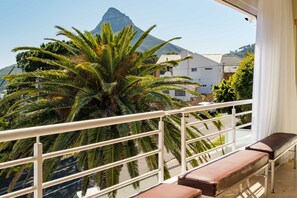 Un balcon offrant une vue sur une montagne, des palmiers et une balustrade blanche.