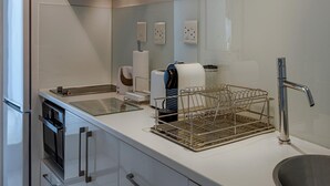Une cuisine moderne dotée d’un four encastré, d’un évier en acier inoxydable et d’un égouttoir à vaisselle.