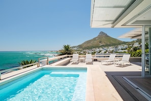 A rooftop pool with a clear view of the ocean and a mountain in the distance.