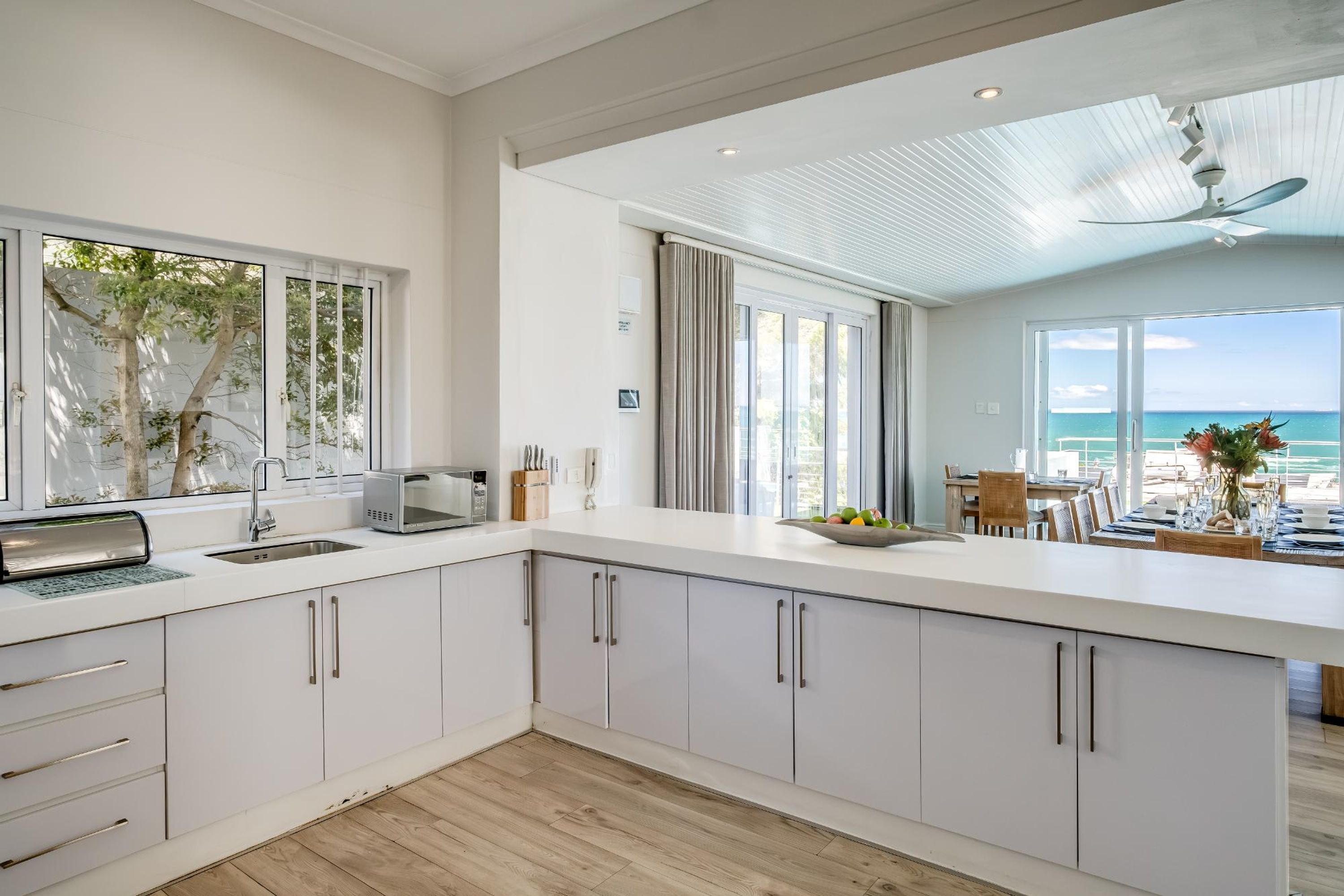 Een moderne keuken met witte kastjes, een ingebouwde magnetron en een groot kookeiland met een spoelbak.