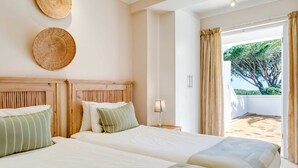 Une chambre d’hôtel avec deux lits, une tête de lit en bois, un chapeau accroché au mur et une vue sur l’extérieur.