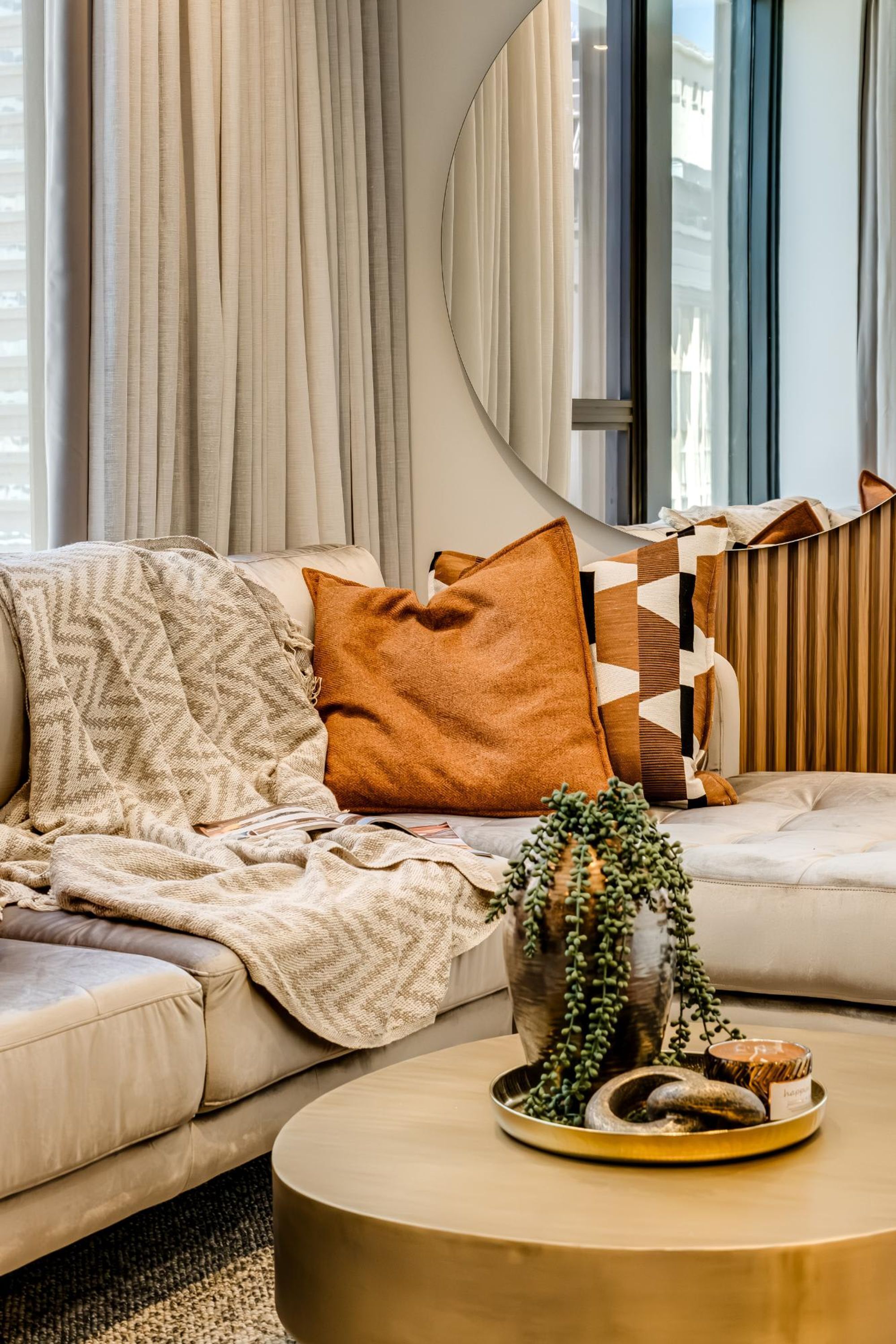 Un soggiorno moderno con un divano beige, un tavolino rotondo e una pianta decorativa.