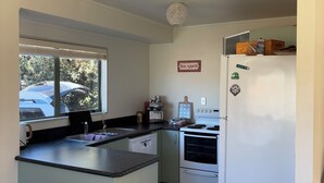 Cocina compacta con una isla central, un refrigerador, estufa y ventana con vista a un estacionamiento.